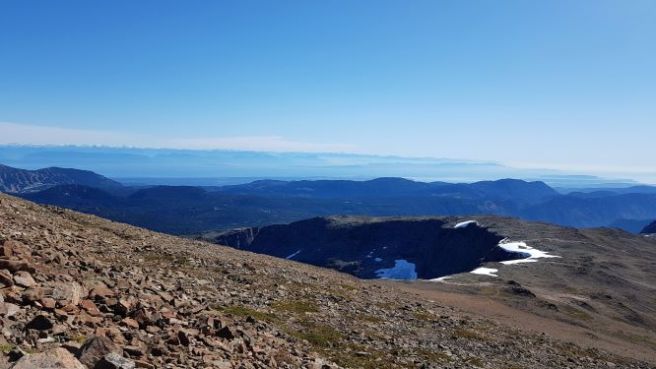 The ridge of a rocky mountain curves to the left. Traces of snow is visible on the ridge.
