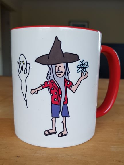 A white coffee mug features a doodle of a casually dressed Gandalf throwing an atom at a ghost. The mug handle is red.
