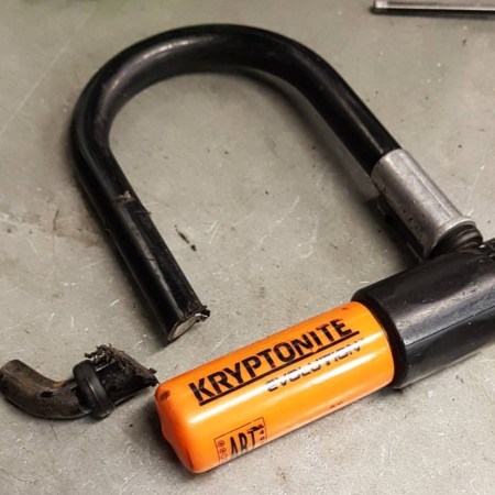 A black and orange Kryptonite Evolution u-lock showing a piece cut out.