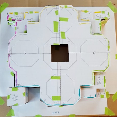 Birds eye view of the cardboard structure. The border of each side is colour coded, and in the middle there is a void. Green tape can be seen holding the structure together.
