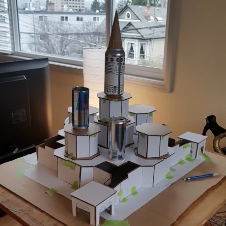 Pieces of cardboard with grid paper glued to them form an unfinished 3D model of St. Basil's Cathedral.