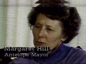 An older white woman with short curly dark hair looks away from the camera. Text on the bottom left reads: Margaret Hill Antelope Mayor.