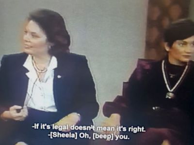A white woman in a white blouse and dark blue blazer looks away from Sheela, seated on the right. The text reads: If it's legal doesn't mean it's right. Sheela: Oh, beep you.