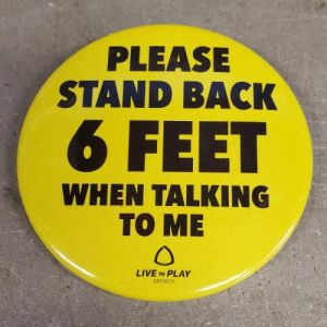 A yellow button reads PLEASE STAND BACK 6 FEET WHEN TALKING TO ME.