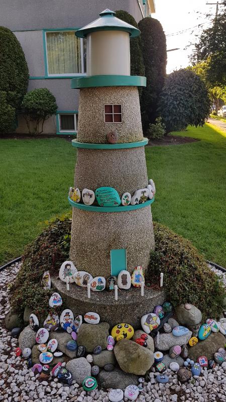A miniature model of a lighthouse surrounded by painted rocks.