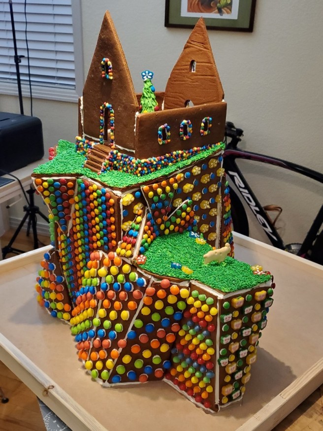 A partially decorated gingerbread structure shows a Christmas tree inside a house before the roof went on.