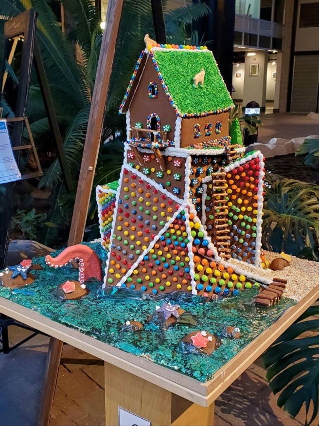 The completed gingerbread creation on display. The pier, ladder, boulders, tentacle, and rooftop goats are visible.