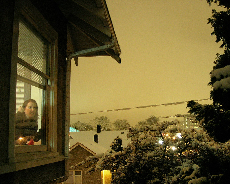 A yellow hued photo showing me shaking my fist from behind a window. A snowscape is visible in the background.
