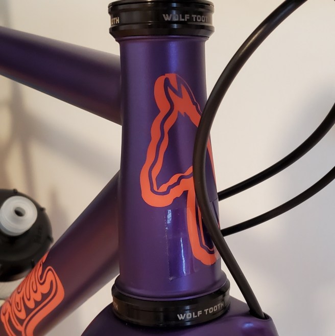 Close up of the tapered head tube with the horse logo painted on front. A piece of clear tape can be seen on the lower part of the head tube.